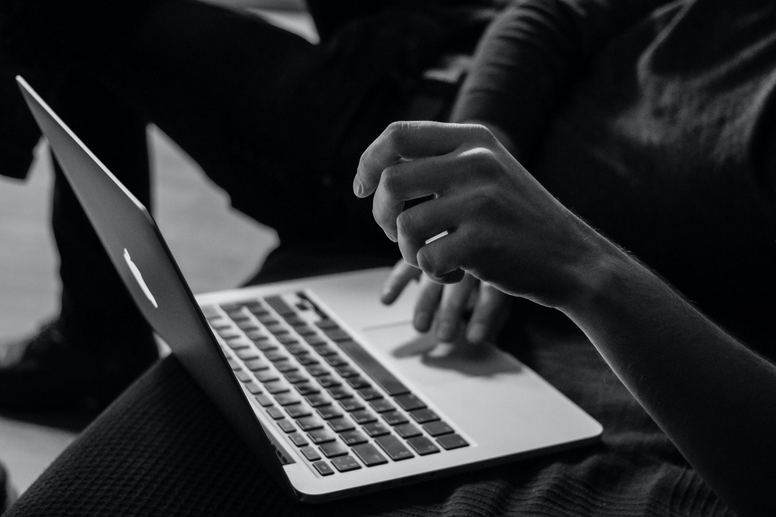 Widok na otwarty laptop, na klawiaturze dłonie programisty
